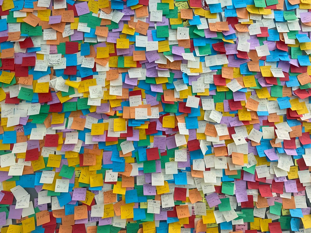 Un mur densément recouvert de notes autocollantes multicolores.